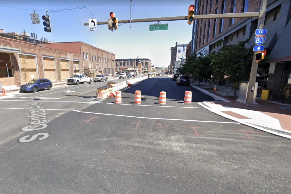 Old brick buildings line Central Avenue in Baltimore. The street is filled with construction equipment.